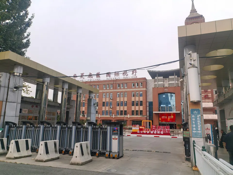 校门口：电动伸缩门、水泥墩、正对面的教学楼